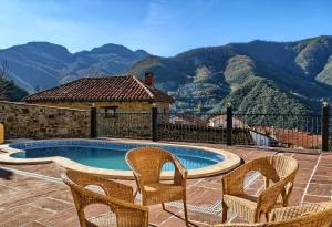 a patio with two chairs and a swimming pool with mountains at Posada Valle del Oso in Lerones