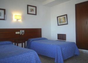 dwa łóżka w pokoju z niebieską pościelą w obiekcie Hotel Marina Victoria w mieście Algeciras +22 zdjęcia