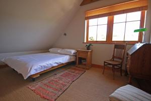 a bedroom with a bed and a chair and a window at Netherton Farm B&B in Culbokie