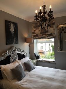 a bedroom with a bed with a chandelier and a window at The White House Hotel in Newquay