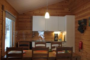 una cucina con tavolo, sedie e armadietti bianchi di Villa Hilda, cottage by the lake a Posio