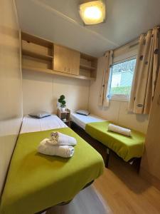 two beds in a room with green sheets and a window at Séjour Idéal en Mobil-home 6 à 8 Personnes in Pont-de-Salars