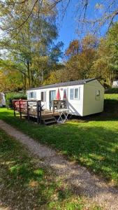 a trailer is parked in the grass near a path at Séjour Idéal en Mobil-home 6 à 8 Personnes in Pont-de-Salars