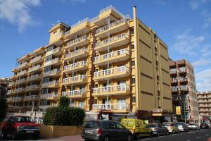 un gran edificio amarillo con coches estacionados frente a él en Skyview Hotel Tenerife, en Puerto de la Cruz