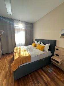 a bedroom with a large bed with yellow pillows at Lavanttalbahn Suite in Bad Sankt Leonhard im Lavanttal