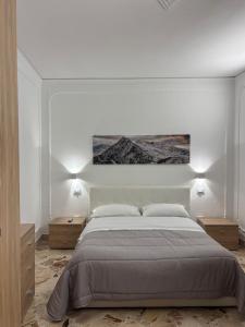 a white bedroom with a large bed and two night stands at Appartamento San Vito in Piana degli Albanesi