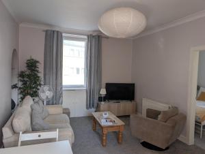 a living room with a couch and a tv at Scott Street Modern Flat in Galashiels +2 photos