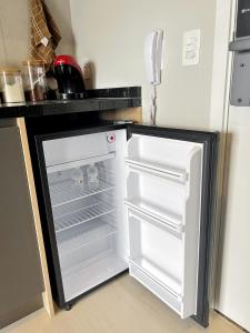 an empty refrigerator with its door open in a kitchen at Modern Studio Brooklin 230 meters from the subway in Sao Paulo