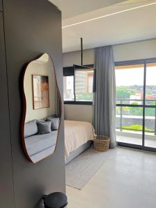 a bedroom with a mirror and a bed and a window at Modern Studio Brooklin 230 meters from the subway in Sao Paulo