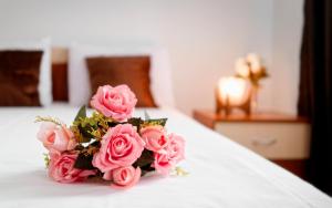 ein Strauß rosa Rosen auf einem Bett in der Unterkunft ,, LA MAISON CONCORDIA '' in Cincu