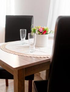 einen Tisch mit einer Schüssel Blumen und Gläsern darauf in der Unterkunft ,, LA MAISON CONCORDIA '' in Cincu