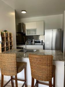 a kitchen with a counter and two bar chairs at Beach apartment playa caracol in Chame