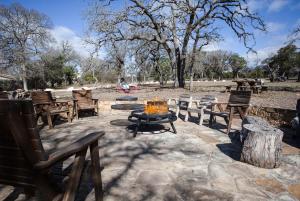 a fire pit with benches and a table and chairs at Hill Country Retreat - 1BR Cabin w Nature Views in Ingram