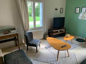 a living room with a table and a television at Les Vendanges Maison Vigneronne in Reuilly