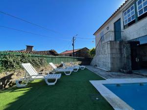 une rangée de chaises de jardin assises à côté d'une piscine dans l'établissement Casa do Capitão de Cutelo - Gerês, à Terras de Bouro