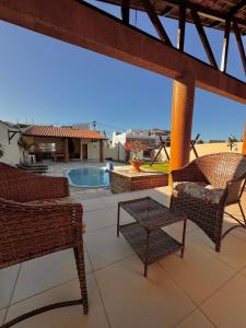 eine Terrasse mit Korbstühlen und einem Pool in der Unterkunft Casa du Vento in Cruz
