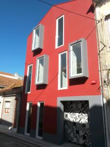 a red building with white windows on a street at Aveiro Rossio Bed & Breakfast in Aveiro