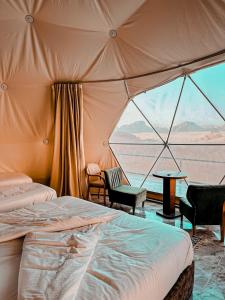a tent with a bed and chairs and a table at Rum warm bubble camp in Wadi Rum