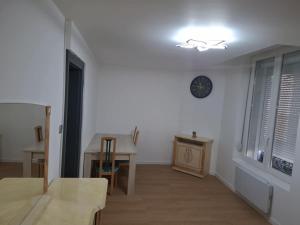 a living room with a table and a clock on the wall at Appartement cosy in Charleville-Mézières
