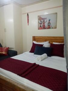 um quarto com uma cama grande com almofadas vermelhas e azuis em Mo Homes - Studio in South B, 15mins from JKIA, Wilson Airport & Nairobi CBD em Nairobi