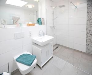 a white bathroom with a sink and a toilet at Alte Druckerei Cicero in Norderney +10 photos