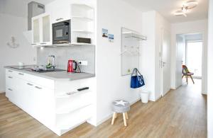 a white kitchen with a sink and a counter at Alte Druckerei Cicero in Norderney