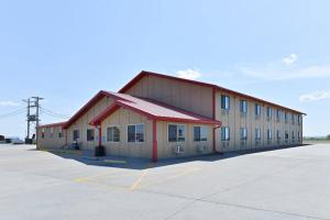 a large building with a red roof in a parking lot at Americas Best Value Inn Kadoka in Kadoka