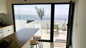 a kitchen and dining room with a view of the ocean at Roque Ocean House - Atlantic Serenity Escape in São Roque