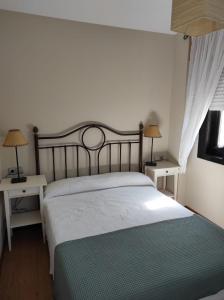 a bedroom with a bed with two tables and two lamps at Apartamento Pelícanos in Fisterra
