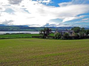 a house in a field next to a lake at Netherton Farm B&B in Culbokie