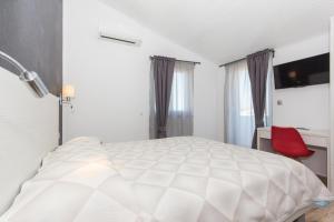 a bedroom with a white bed and a red chair at Alison Apartments in Premantura