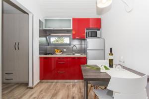 a kitchen with red cabinets and a table with white chairs at Alison Apartments in Premantura
