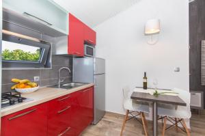a kitchen with red cabinets and a sink and a table at Alison Apartments in Premantura