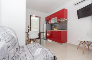 a kitchen with red cabinets and a table with a chair at Alison Apartments in Premantura