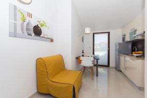 a yellow chair in a kitchen with a table at Alison Apartments in Premantura