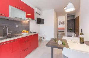 a kitchen with red cabinets and a wooden table at Alison Apartments in Premantura