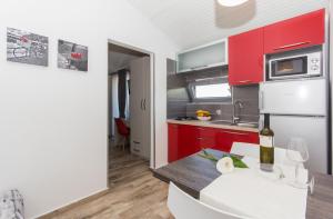 a kitchen with red cabinets and a table with a bottle of wine at Alison Apartments in Premantura