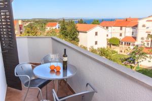 a table with a bottle of wine and oranges on a balcony at Alison Apartments in Premantura