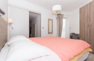 a white bedroom with a large bed with a red blanket at Alison Apartments in Premantura