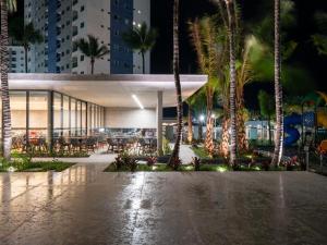 a building with palm trees in a city at night at Salinas Premium Resort in Salinópolis