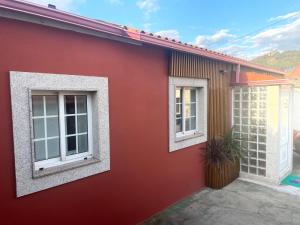 a red house with two windows and a plant at Casa Josefa's in Porriño