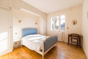 a bedroom with a bed and a table and a chair at Maison 8 pers jardin centre ville 15 min de plages in Lannion