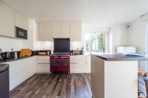 a kitchen with white cabinets and a red stove at Maison 8 pers jardin centre ville 15 min de plages in Lannion
