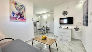 a white living room with a table and a tv at Beautyful Resort Apartment in Haifa