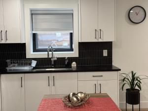 a kitchen with white cabinets and a sink and a window at Calm & Cozy Private Suite in Surrey