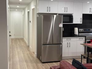 a kitchen with a stainless steel refrigerator and white cabinets at Calm & Cozy Private Suite in Surrey
