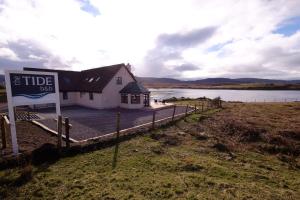 a building with a sign in front of a lake at The Tide in Dunvegan