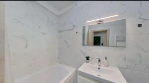 a white bathroom with a sink and a mirror at Mira apartament by Alezzi n10 in Mamaia Nord