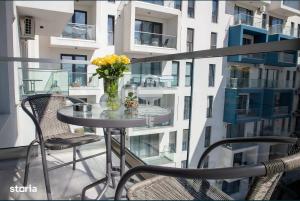 a glass table with a vase of flowers on a balcony at Mira apartament by Alezzi n10 in Mamaia Nord