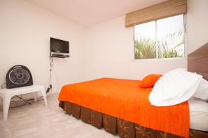 a bedroom with a bed with an orange blanket and a window at Apartamento Cali Camino Real in Cali